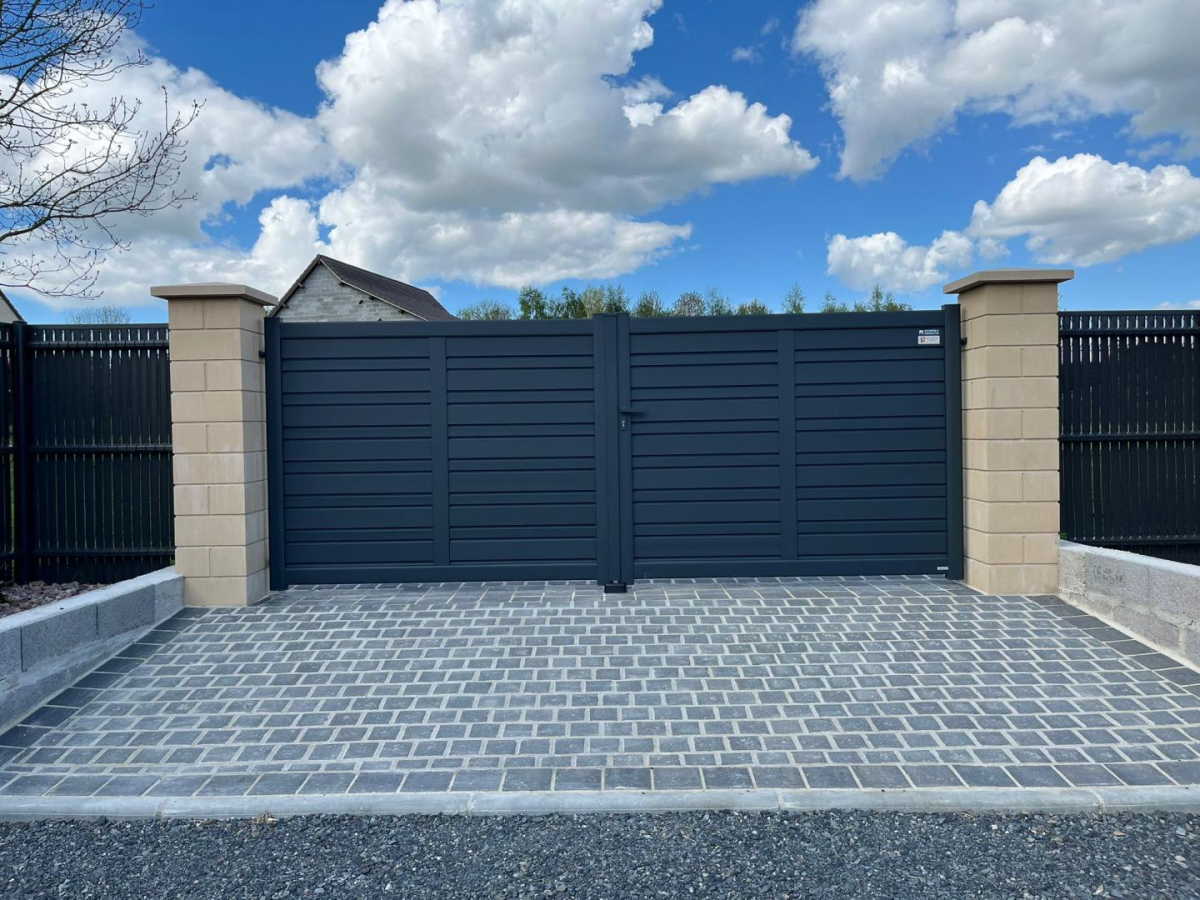 Portail battant alu anthracite lames horizontales entre piliers pierre et paves gris