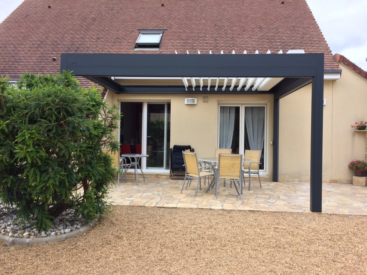 Pergola bioclimatique anthracite a lames blanches orientables sur terrasse en pierre