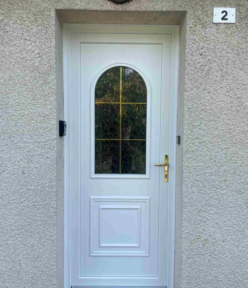 Porte PVC blanche, imposte cintré petits bois dorés, poignée laiton, crépi beige