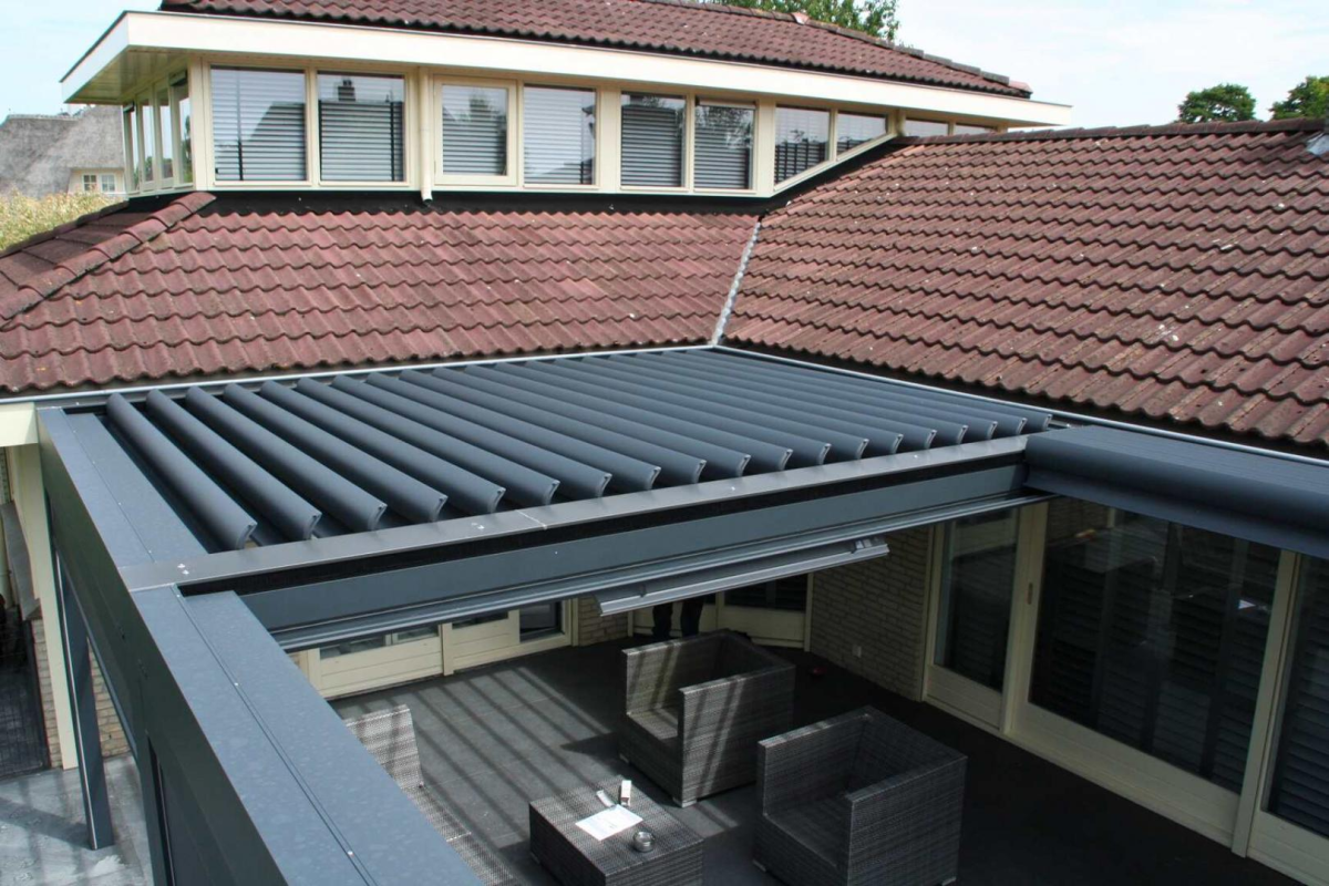 Pergola bioclimatique a lames anthracite partiellement ouvertes sur terrasse avec fauteuils