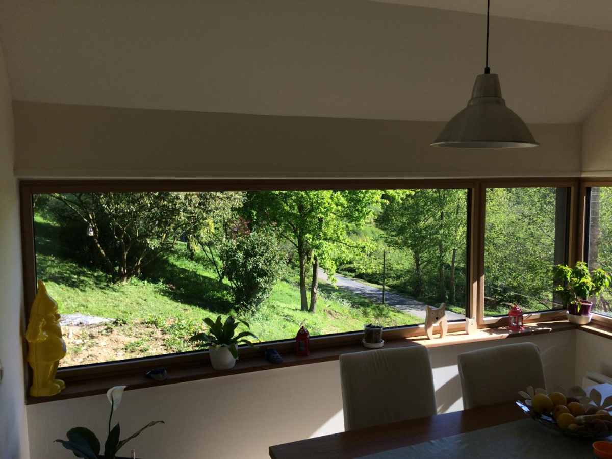 Fenêtre horizontale bois clair, rebord décorations colorées, table salle à manger et jardin