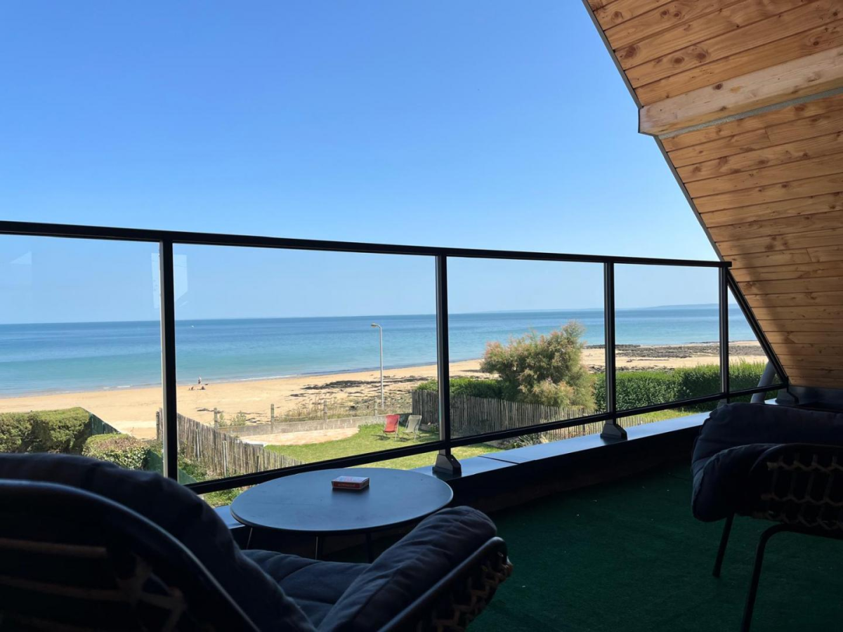 Garde-corps verre et cadre noir sur terrasse verte avec vue mer et transats