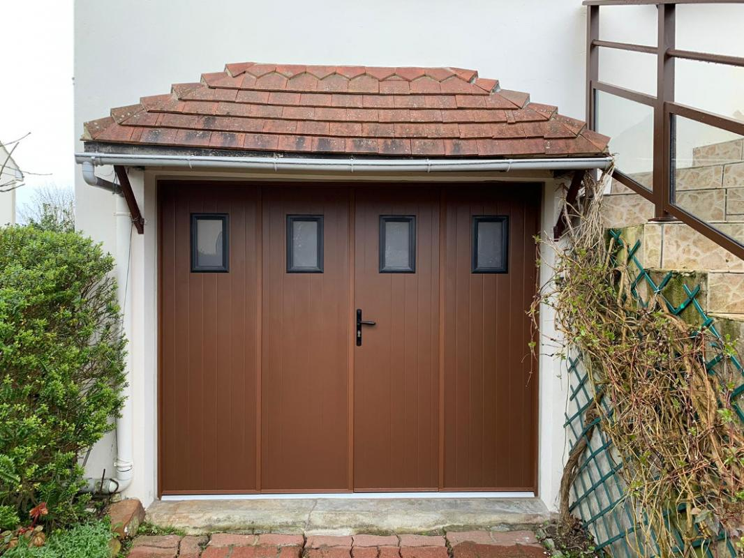 Porte marron quatre vantaux, fenêtres carrées dépolies, auvent tuiles, pavés devant