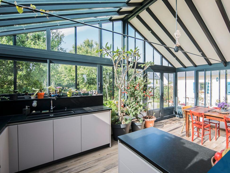 Cuisine moderne sous véranda vitrée avec vue sur le jardin
