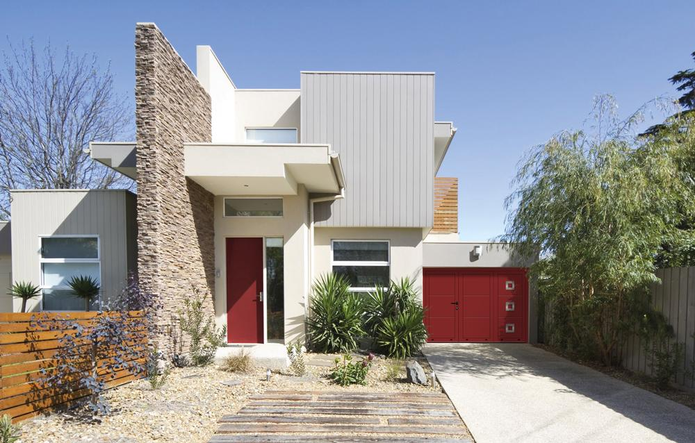 Maison moderne avec porte de garage double rouge à hublots et porte d'entrée assortie
