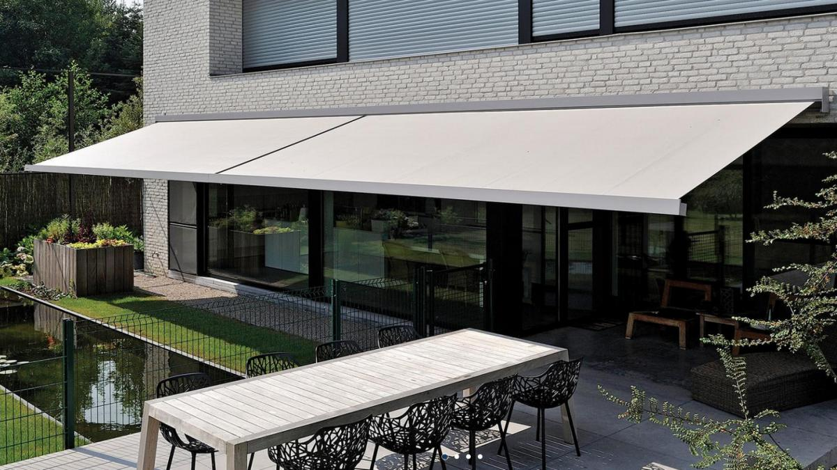 Store banne tendu au-dessus d'une terrasse avec table et chaises