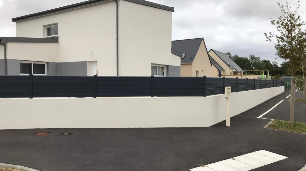 Cloture pleine anthracite lames horizontales sur muret blanc devant maison moderne blanche