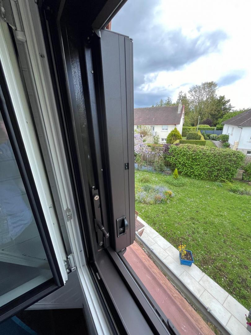 Volet pliant anthracite avec vue sur jardin de maison