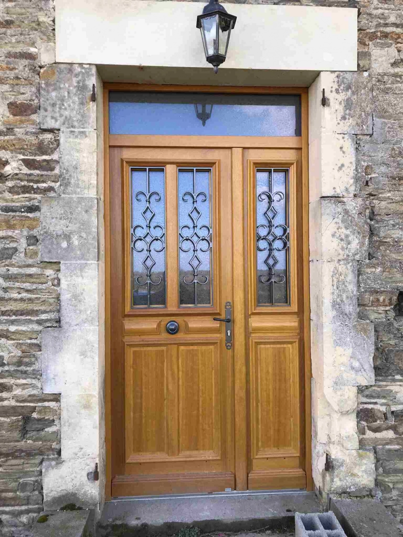 Porte chêne et tiercée, imposte, grilles fer forgé noires, encadrement pierres de taille