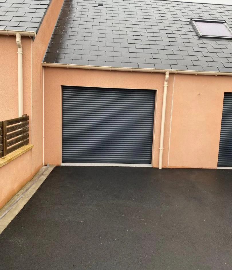 Porte garage enroulable anthracite, crépi saumon, toit ardoise et fenêtre de toit
