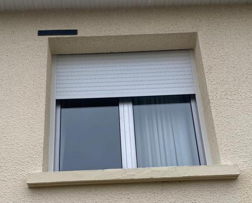 Fenêtre alu, volet roulant blanc à mi-hauteur, rideaux blancs, mur crépi beige