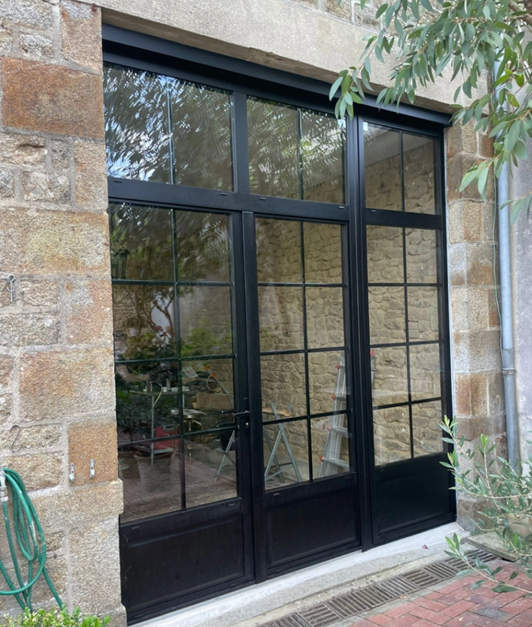 Porte-fenêtre noire style atelier sur pierre, imposte vitrée et seuil briques rouges