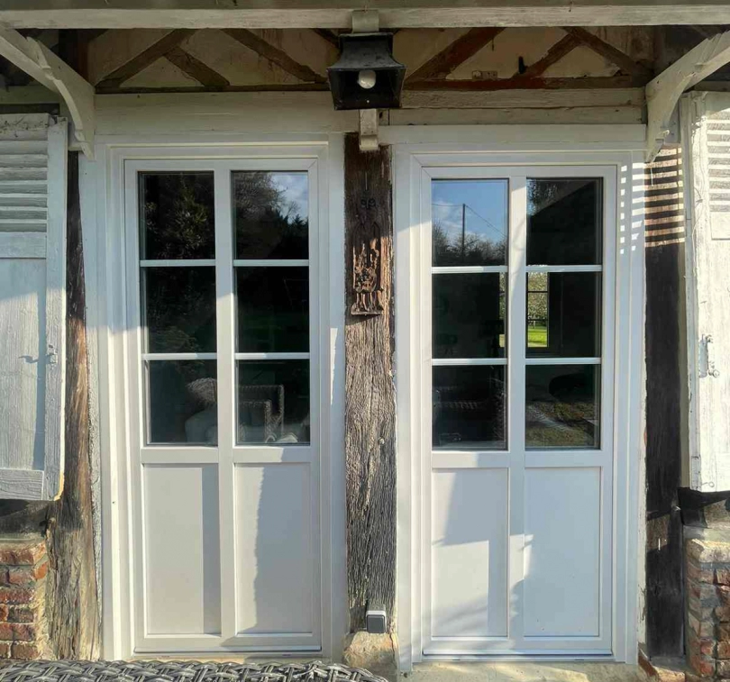 Deux portes vitrees blanches a petits carreaux dans facade colombage et bois patine