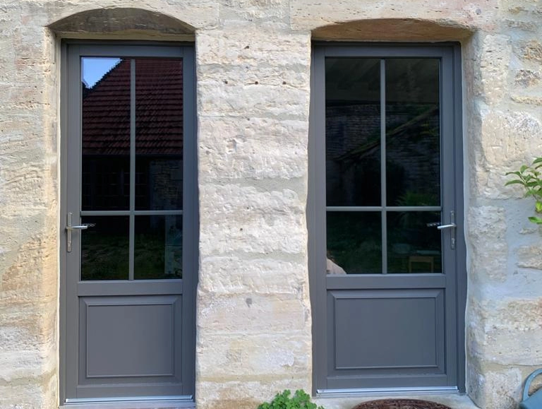 Deux portes gris anthracite vitrées croisillons dans mur pierre, seuils bois et pierre