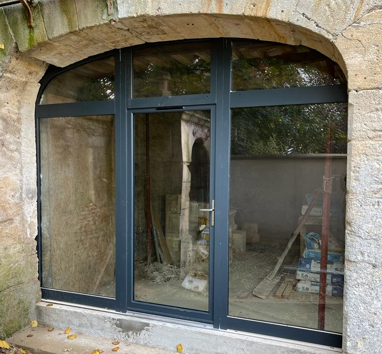 Menuiserie anthracite à trois parties sous arc en pierre, chantier de rénovation