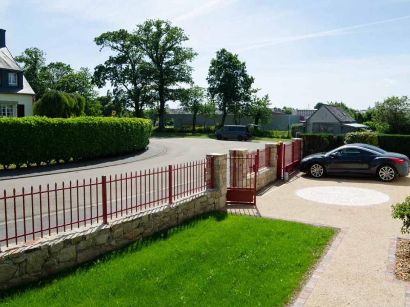 Clôture et portail rouge bordeaux à barreaux pointus sur muret en pierre