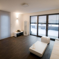 Baie coulissante alu noire à stores intégrés ouvrant sur terrasse enneigée dans salon blanc minimaliste