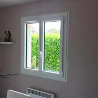 Fenêtre blanche deux vantaux vue intérieure, mur mauve et haie verte visible à travers les vitres