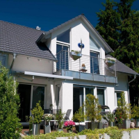 Maison blanche deux niveaux, lucarne vitrée, balcon barreaudage métal et terrasse fleurie en pots