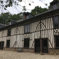 Grande maison colombages bois sombre, motifs ogive, lucarnes et cour en gravier clair