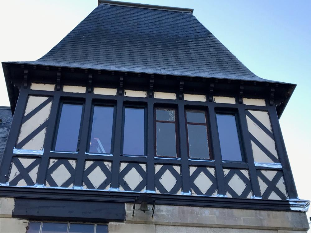 Façade colombages avec rangée de fenêtres anthracite étroites sous toit ardoise gris pentu