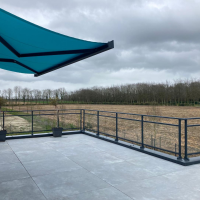 Garde-corps alu anthracite sur terrasse carrelée, voile d'ombrage turquoise et campagne