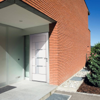 Porte d'entrée PVC blanche bandes métal horizontales, imposte vitrée dépolie et mur briques rouges