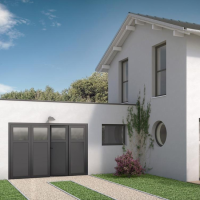 Maison blanche, porte garage gris anthracite quatre vantaux vitrés, fenêtre ronde et allée gravier