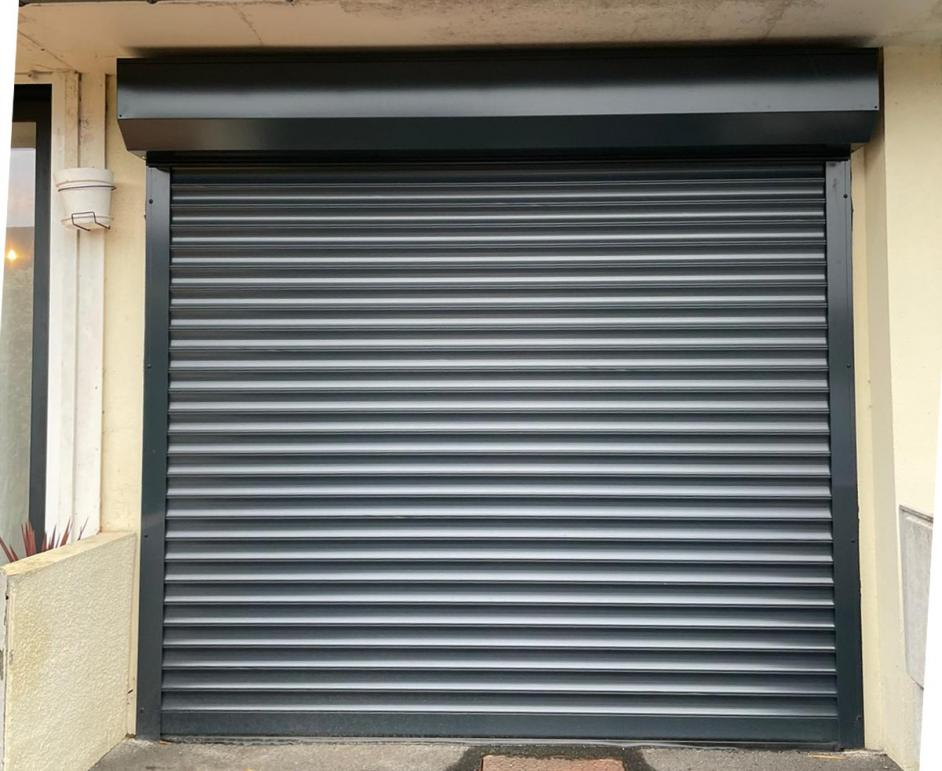 Porte enroulable anthracite fermée, lames horizontales, coffre et coulisses sur façade beige claire