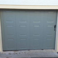 Porte garage pliante vert olive, quatre panneaux verticaux à moulures rectangulaires, poignée noire