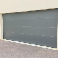 Porte sectionnelle gris anthracite lisse, quatre panneaux horizontaux sur façade claire