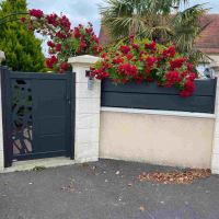 Portillon anthracite à motif découpé laser, clôture assortie sur muret et rosiers rouges