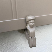 Arrêt de volet taupe en tête de bergère, maintient un volet battant beige contre mur blanc crépi