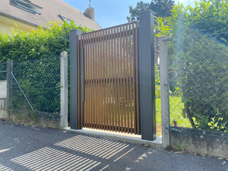 Portillon à lames bois verticales et cadre anthracite entre poteaux gris