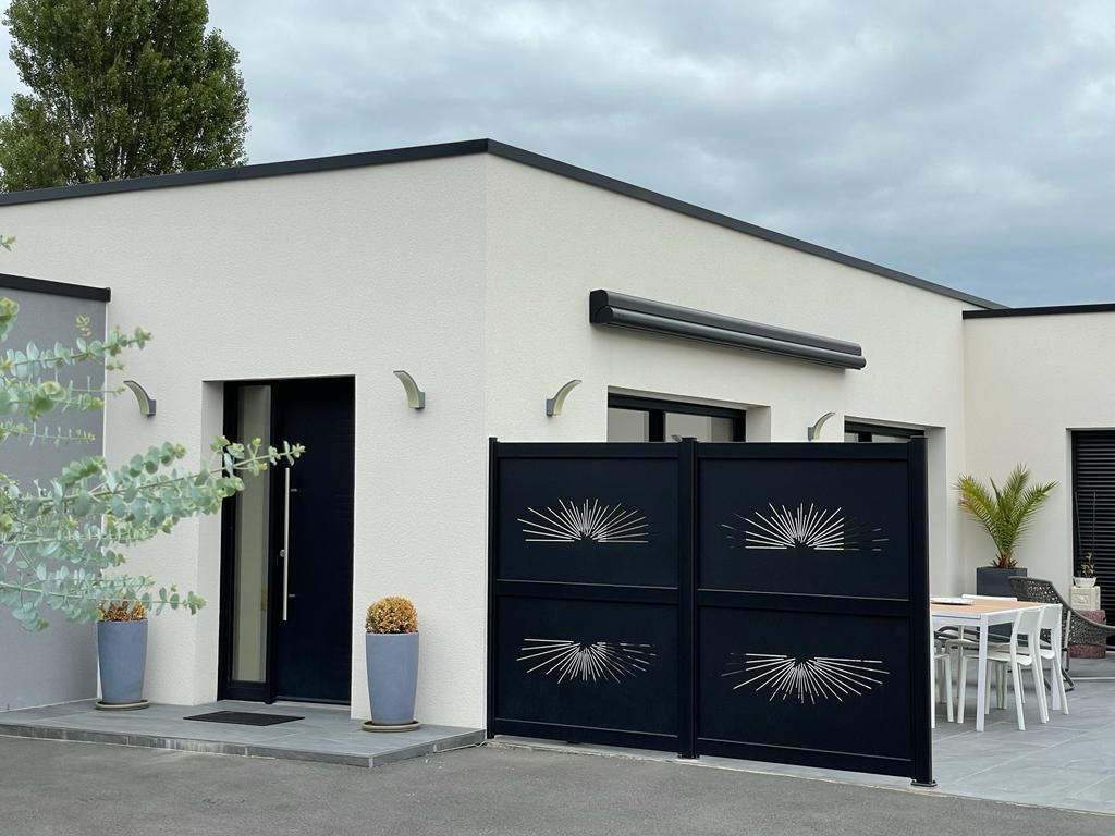 Claustra noir à motifs rayonnants devant façade blanche et porte d'entrée