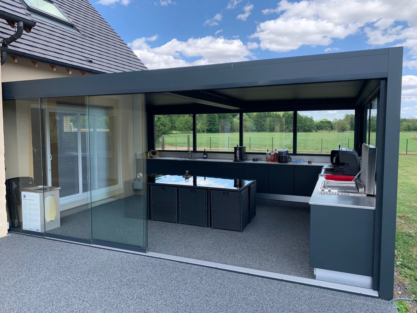 Pergola anthracite cuisine extérieure, parois vitrées coulissantes, sol résine gris