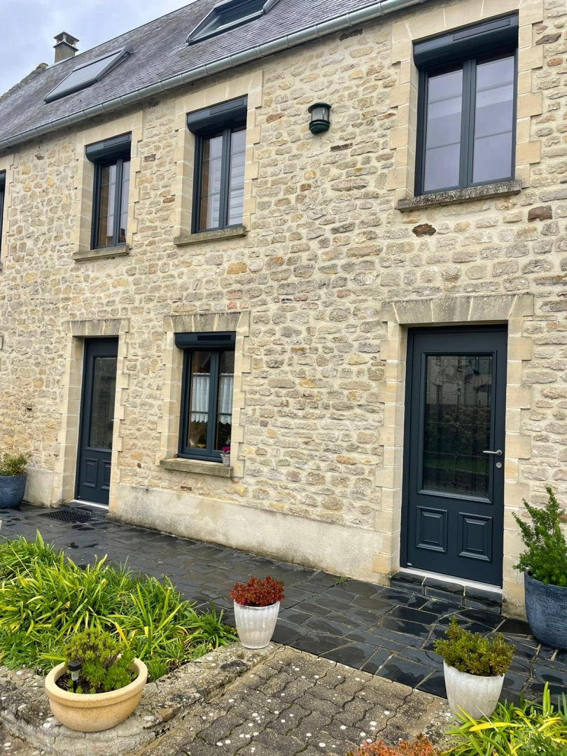 Menuiseries anthracite sur maison pierre, volet roulant solaire, terrasse ardoise