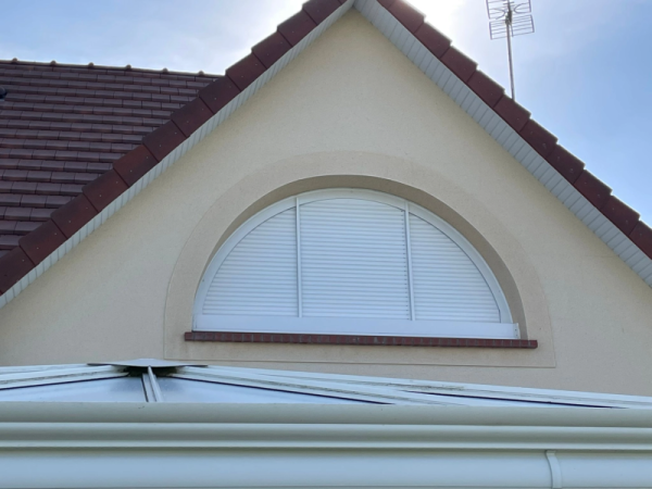 Volet roulant blanc cintré plein cintre sous pignon tuiles rouges, façade beige