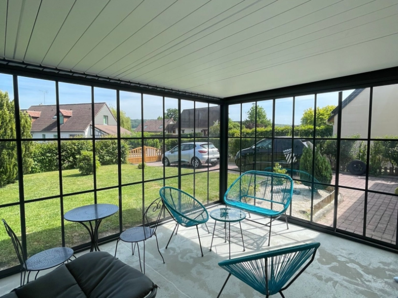 Véranda alu noir style atelier, vitrage quadrillé, toit panneaux blancs, jardin