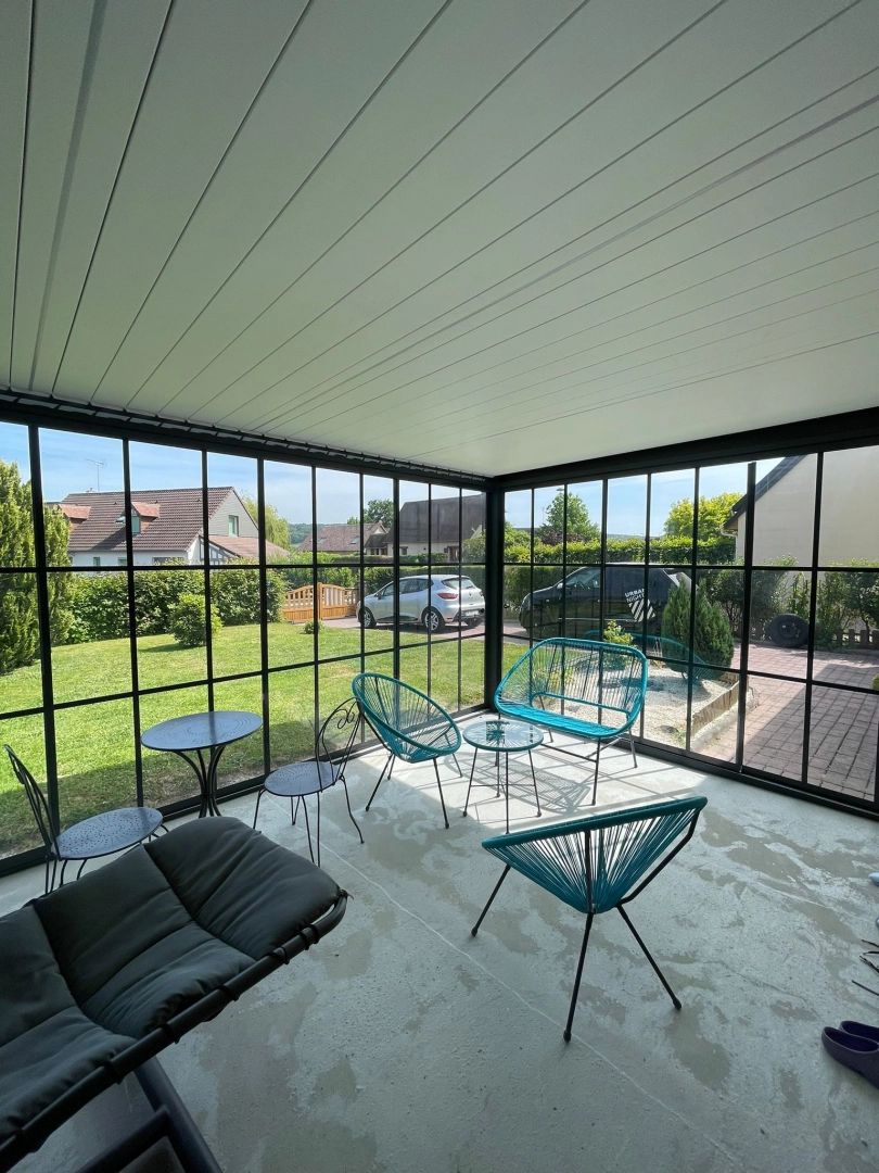 Véranda alu noir style atelier, vitrage quadrillé, toit panneaux blancs, jardin