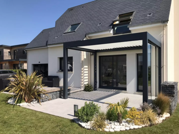 Pergola bioclimatique anthracite, lames claires, paroi vitrée coulissante, terrasse dalles grises