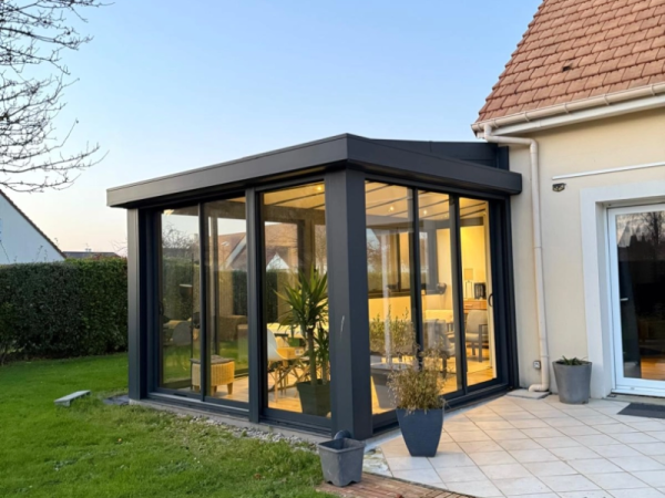 Véranda anthracite baies coulissantes, terrasse carrelée claire devant maison tuiles