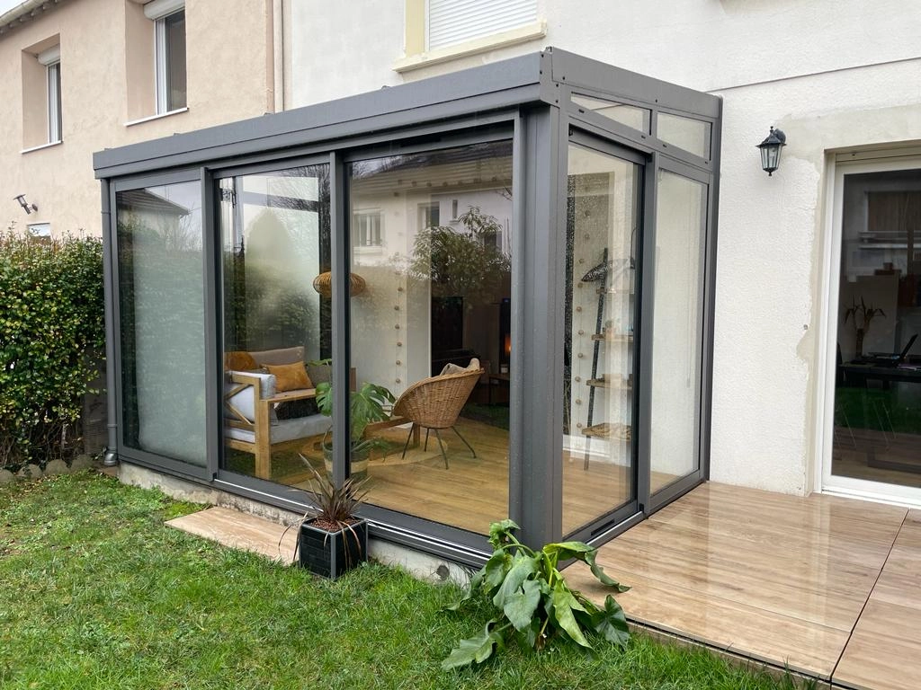 Véranda alu anthracite toit plat, baies coulissantes, dalle béton et pelouse