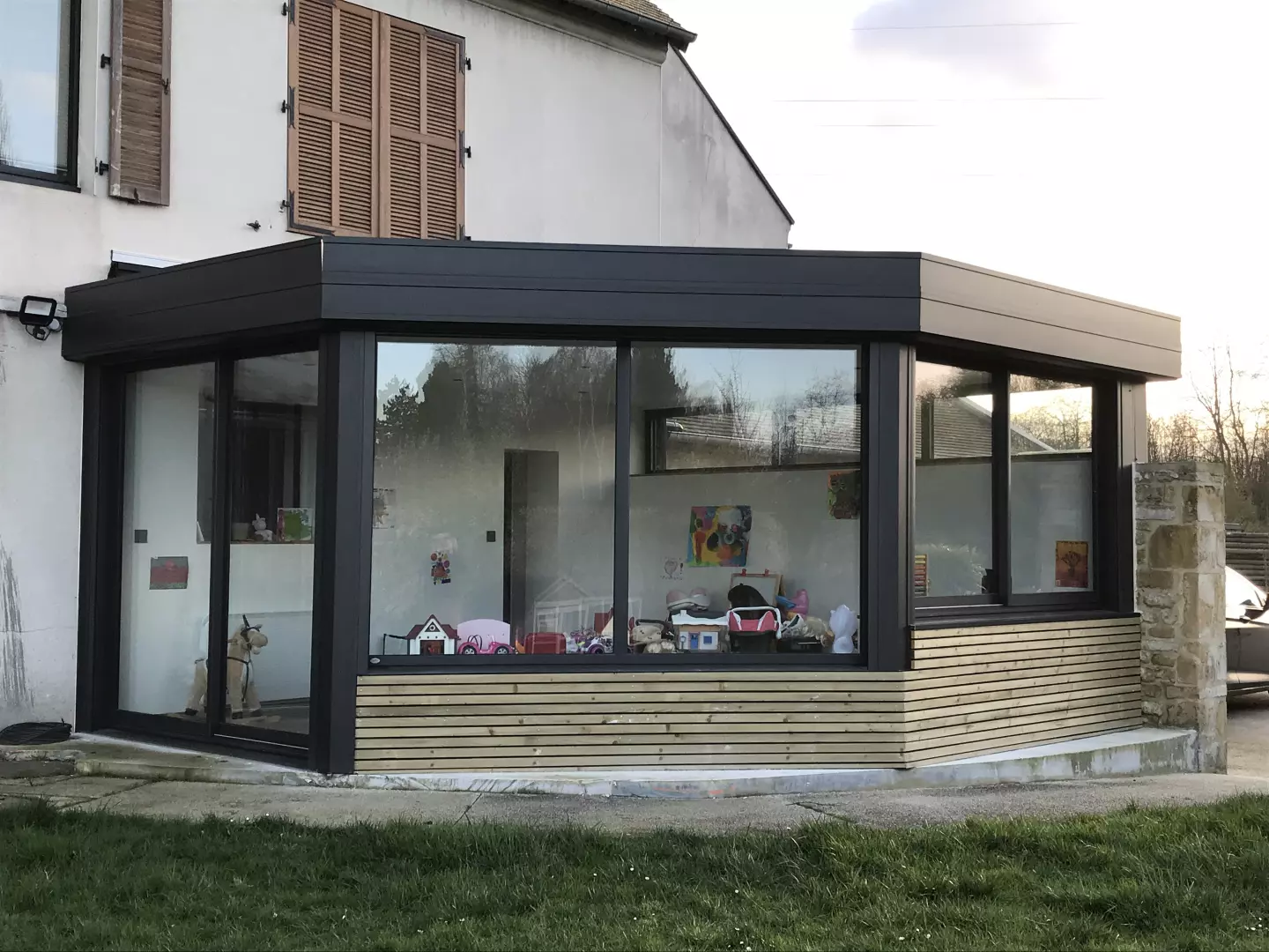 Extension toit plat alu anthracite et bardage bois clair, grandes parois vitrées