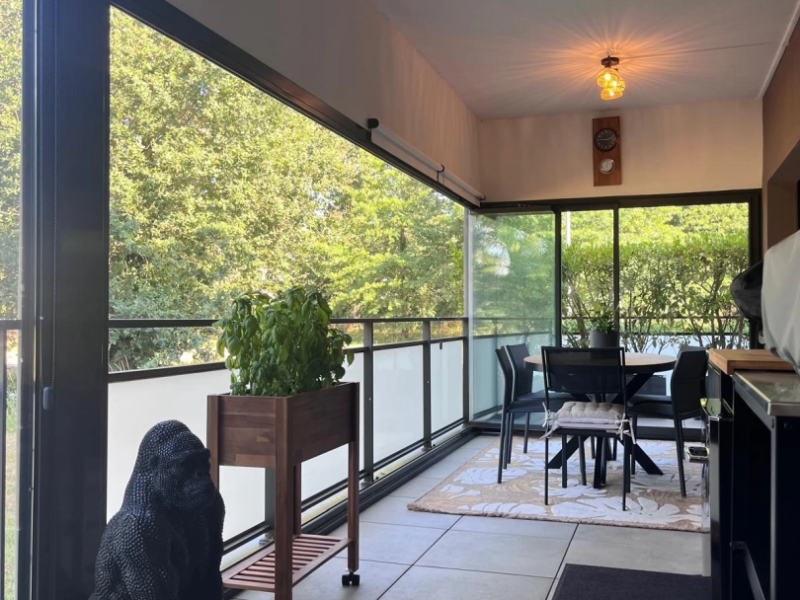 Balcon fermé par coulissantes alu anthracite, garde-corps verre, vue arbres