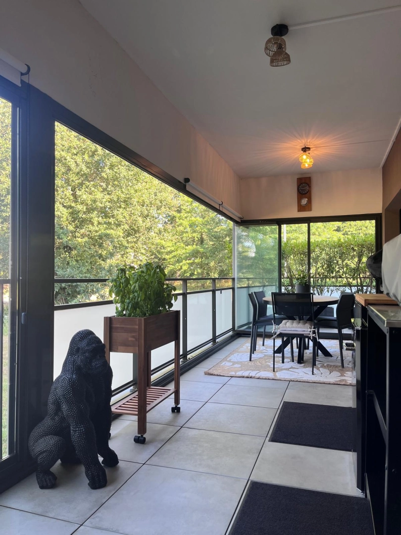 Balcon fermé par coulissantes alu anthracite, garde-corps verre, vue arbres