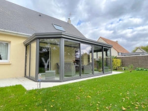 Veranda anthracite baies vitrees angle chanfreine, pelouse et toit ardoise