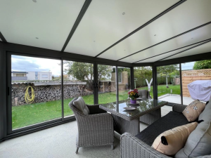 Interieur veranda grise, spots LED, salon resine tressee et vue jardin
