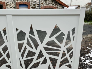 Gros plan panneau portail blanc motifs géométriques ajourés, gravier et neige