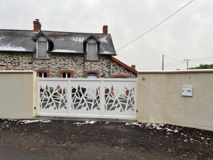 Portail coulissant blanc motifs shards, maison pierre ardoise et muret crépi